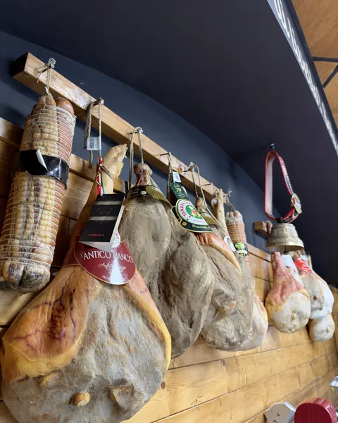 Prosciutti e salumi appesi alla parete di legno